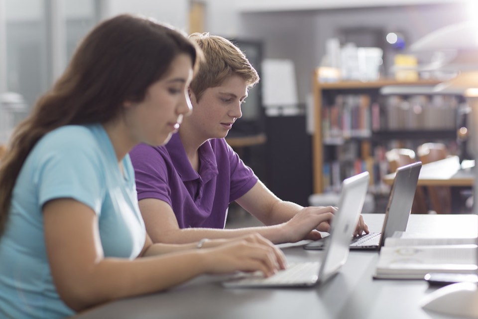 Estudiantes trabajando con laptops en la biblioteca